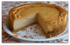 A creamy cheesecake with a slice removed on a decorative plate.