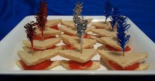 Triangular sandwiches with colorful decorative picks on a platter.