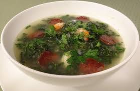 Bowl of leafy green soup with tomatoes and herbs.