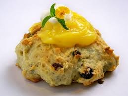 Scone topped with lemon curd and a mint leaf.
