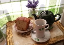 A cozy tea setup with cake and a teapot on a lace tablecloth.