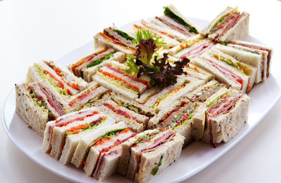 A plate of assorted finger sandwiches with colorful fillings.