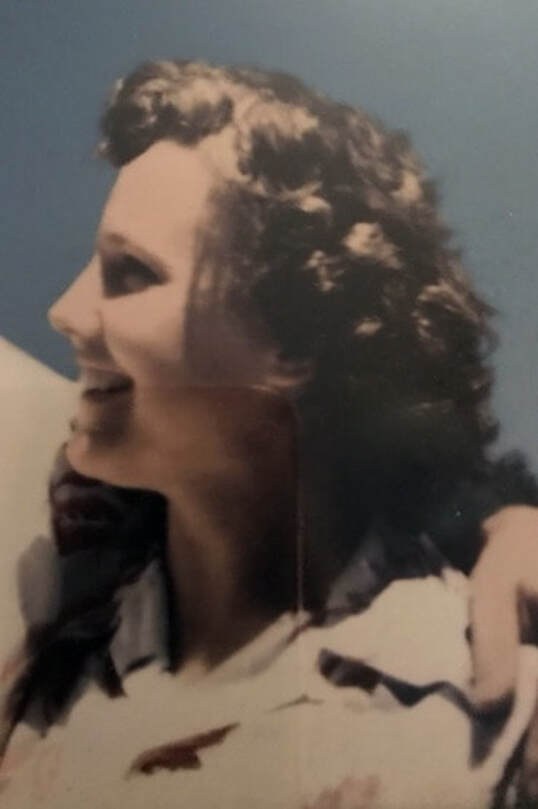Smiling woman with curly hair in a vintage-style photo.