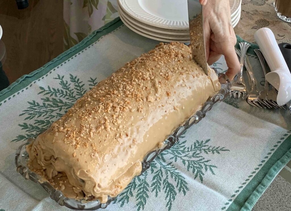 Cake being sliced on decorative tablecloth.
