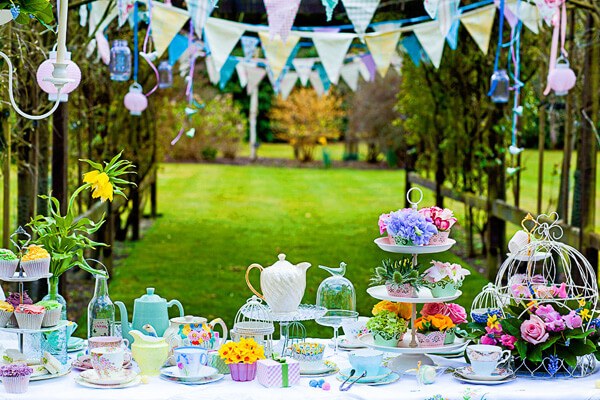 A whimsical outdoor tea party setup with colorful decorations and treats.