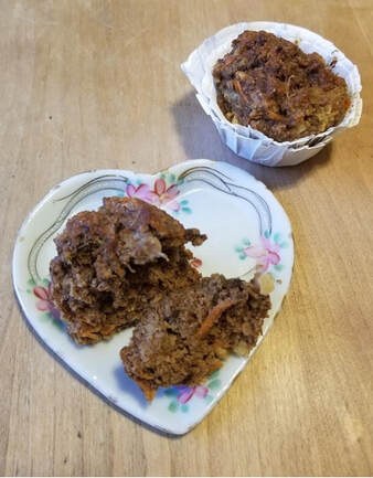 Two chocolate muffins, one halved, on a floral heart-shaped plate.
