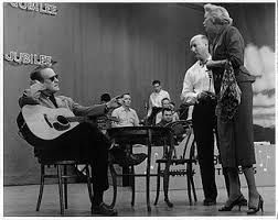 Actors rehearsing a scene with a guitar in a theater setting.