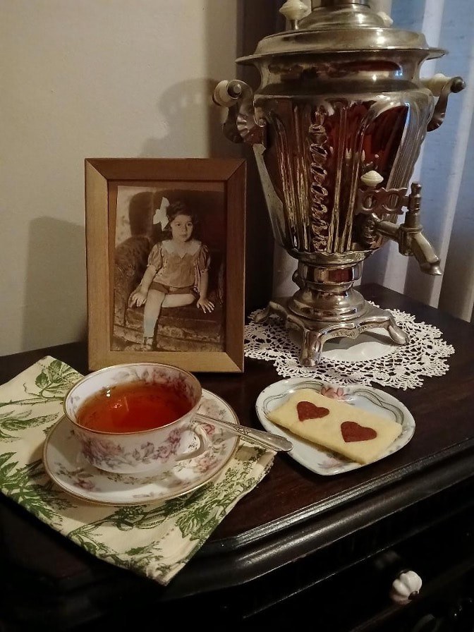 A vintage tea setup with a cup of tea, biscuits, and an old photograph.