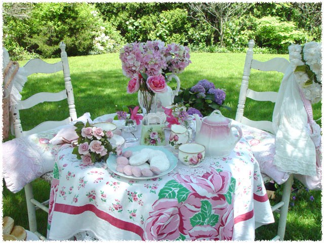 Charming outdoor tea party setup with floral decor and pink roses.