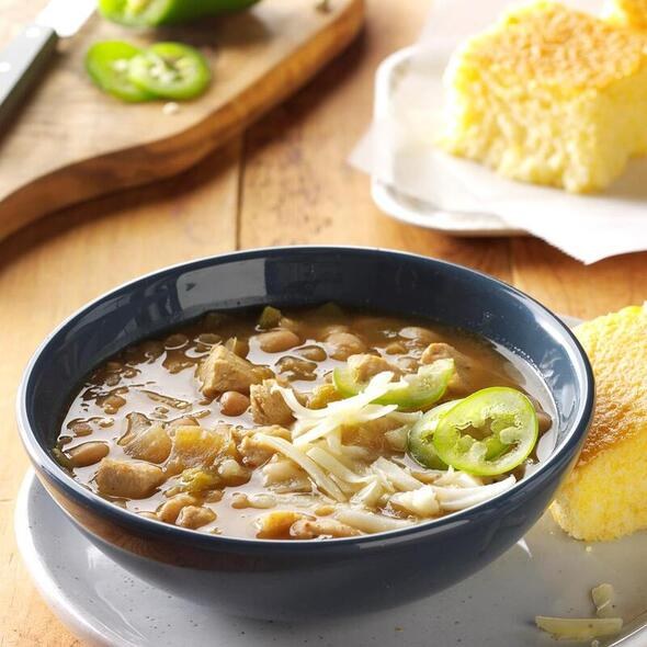 A bowl of hearty soup garnished with jalapeños and onions.