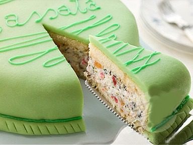 A slice of green marzipan cake with cream and fruit filling.