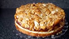 A delicious almond-topped cake on a dark surface.