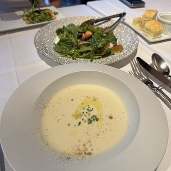 Creamy soup served with a fresh salad on a white table.