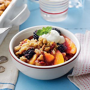 A bowl of fruit crisp topped with whipped cream and mint.