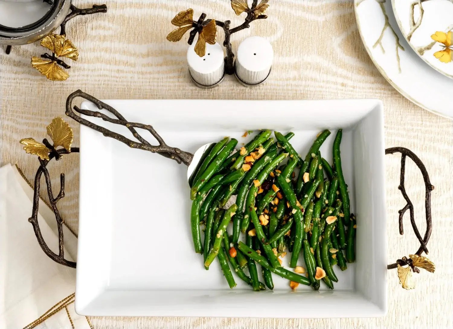 A white rectangular plate with sautéed green beans garnished with garlic.