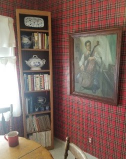 Cozy room corner with red plaid wallpaper and a framed angel painting.
