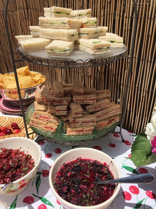 Tiered stand with assorted sandwiches and bowls of berries.