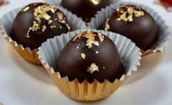 Close-up of chocolate truffles with nut toppings in paper cups.