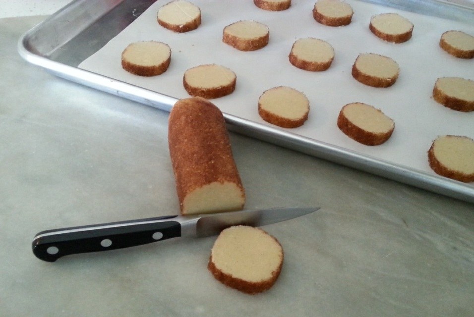 Sliced bread roll next to a baking tray with arranged slices.