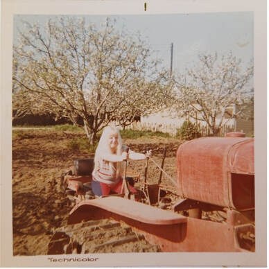 Person cooking outdoors near an old tractor in a rustic setting.