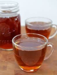 Two clear glass cups filled with tea and a jar of honey.
