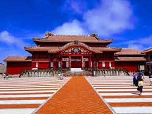 The vibrant red Shuri Castle under a bright blue sky.