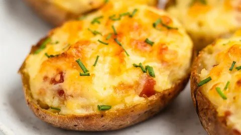 Close-up of a cheesy, stuffed baked potato topped with chopped chives.