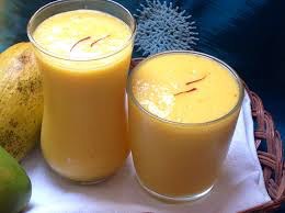 Two glasses filled with creamy mango lassi topped with saffron strands.