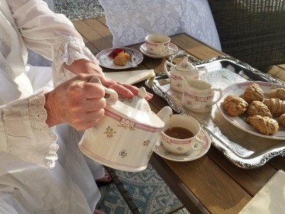 Tea being poured with scones and cups.