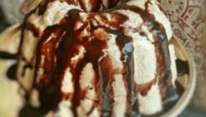 Close-up of creamy dessert drizzled with rich chocolate sauce.