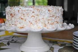 A coconut-covered cake on a white pedestal.