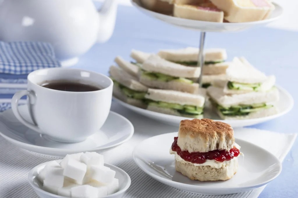 Afternoon tea setup with tea, scones, and finger sandwiches.