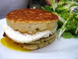 Stack of savory potato pancakes with a dollop of sour cream and fresh salad.