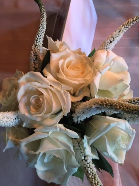 Elegant white roses with textured, natural accents in soft lighting.