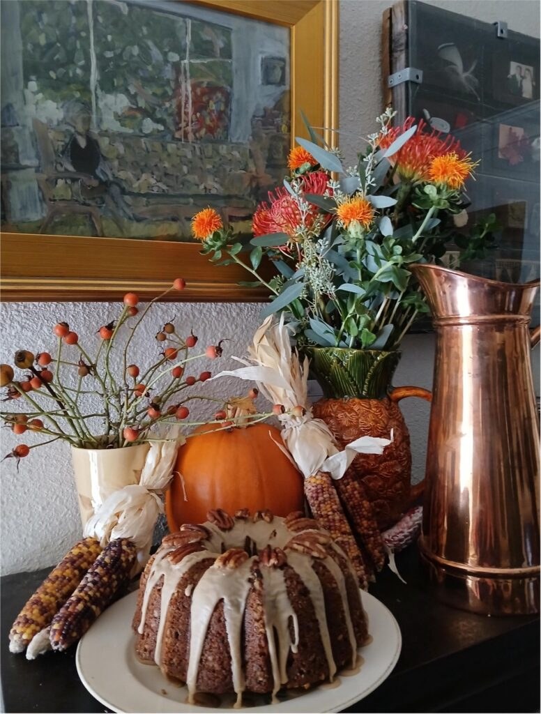 A cozy autumn arrangement with pumpkin, flowers, and baked goods.