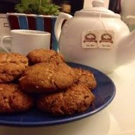 Plate of homemade cookies next to a teapot and cups.