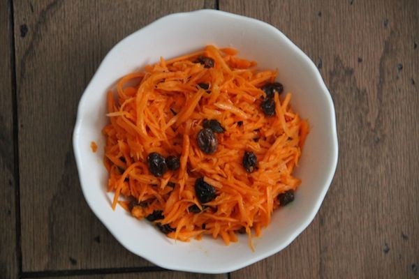 Bowl of shredded carrot salad with raisins.