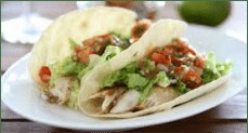 Two soft tacos filled with grilled chicken, lettuce, and salsa.