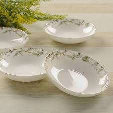 Set of four white plates with floral patterns on a beige surface.