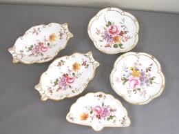 Set of five vintage porcelain plates with floral designs and gold trim.