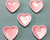 Pink heart-shaped ceramic dishes with white centers on a gray surface.