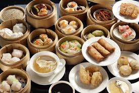 A variety of dim sum dishes in bamboo steamers and plates.