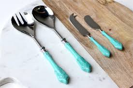 Silver serving utensils with turquoise handles on a wooden surface.