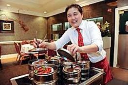 A smiling chef serving dim sum in a restaurant.