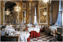 Elegant dining room with ornate decor and chandeliers.
