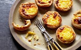 Delicious Portuguese egg tarts on a plate with a fork.