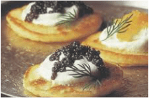 Delicious blinis topped with sour cream, black caviar, and dill.