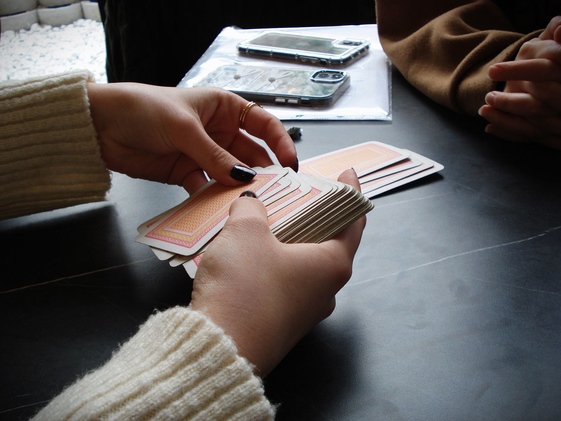 Hands holding playing cards over a table during a game night