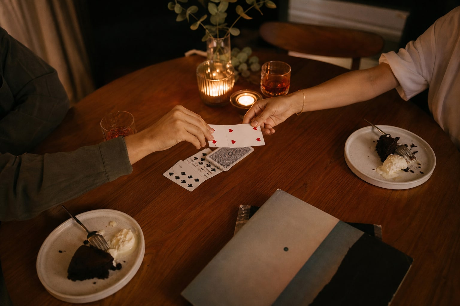 Cards, dessert, and candlelight arranged for a playful date night at home