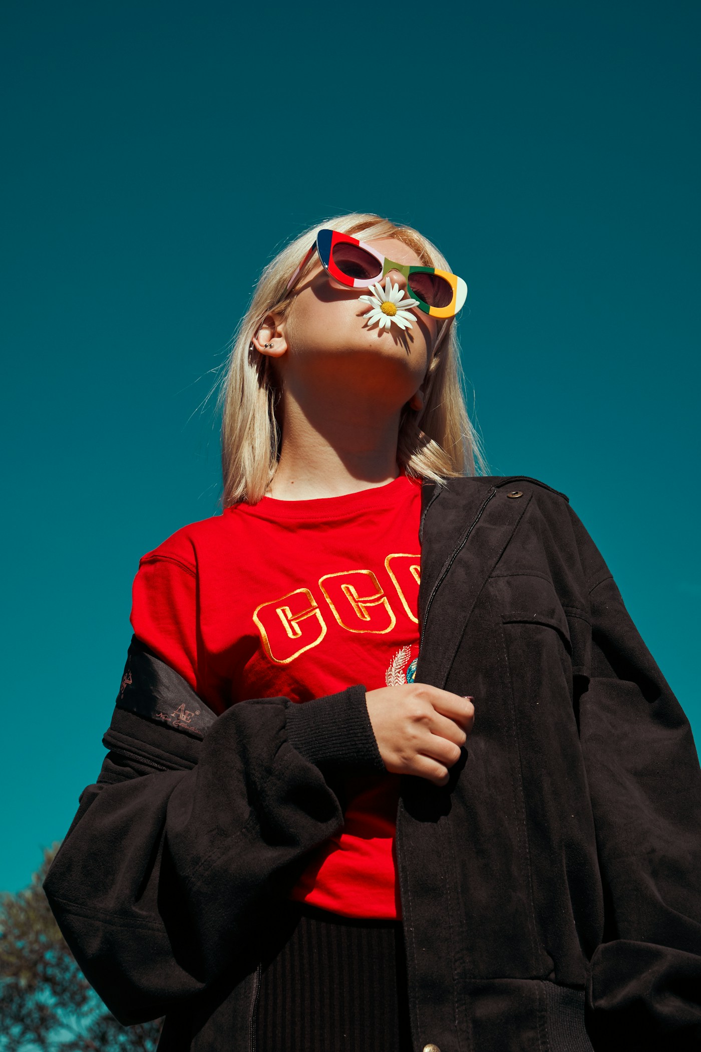 Woman in colorful sunglasses standing outdoors against a deep blue sky